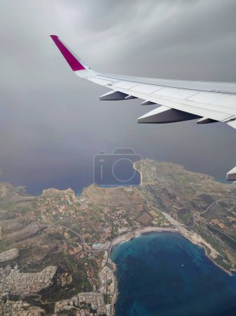 Clouds and a wing of Wizzair airbus from the airplane window. above Malta islands and Mediterranean sea