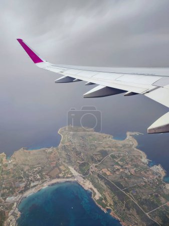 Clouds and a wing of Wizzair airbus from the airplane window. over Malta islands and Mediterranean sea