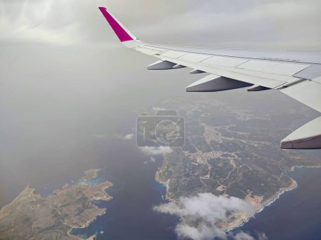 Wolken und ein Flügel des Wizzair-Airbusses aus dem Flugzeugfenster. über Maltas Inseln und das Mittelmeer