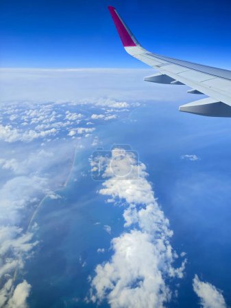 Clouds and a wing of Wizzair airbus from the airplane window. over Malta islands and Mediterranean sea