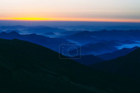 Hermoso amanecer con nubes abajo en las montañas Cárpatos, Chornogora