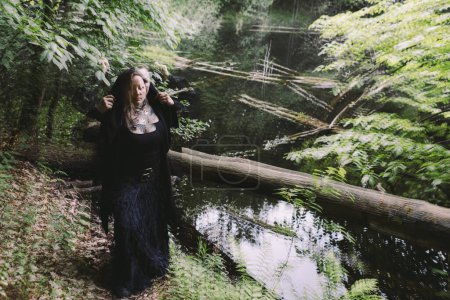 Mujer un negro en el bosque cerca del lago un d swarps, multiexposición