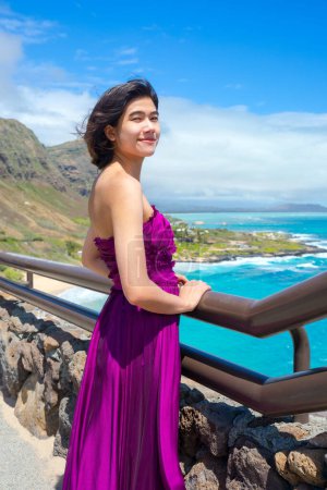 Photo for Young woman in formal purple dress standing at Makapu'u Viewpoint overlooking Makapu'u beach and Hawaiian ocean on Oahu, Hawaii - Royalty Free Image