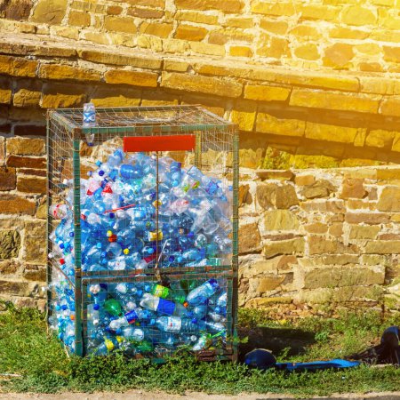 Téléchargez les photos : Poubelle en treillis métallique avec des bouteilles en plastique pour le recyclage, dans le parc à la lumière du soleil. concept de gestion des déchets - en image libre de droit