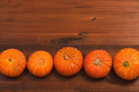 Photo for Autumn orange halloween pumpkins over rustic wooden background. Concept Halloween celebration background, fall harvest, minimalism holiday decoration template. Top view, flat lay, copy space - Royalty Free Image