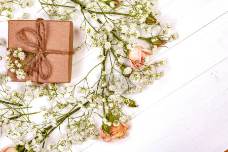 Téléchargez les photos : Aménagement plat de branches et de fleurs sur une table en bois rustique blanc, créant une composition charmante et naturelle - en image libre de droit