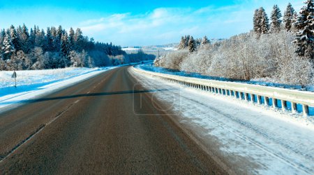 Photo for Winter road trip: asphalt road through snowy forest and scenic snowy landscape with trees in the woods - Royalty Free Image