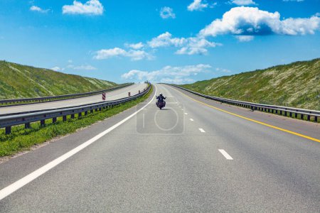 Photo for Highway track with road markings and biker. summer asphalt road under a blue cloudy sky. - Royalty Free Image
