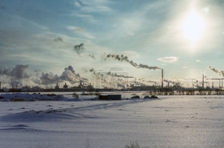 Photo for Industrial winter scenery: smoke and steam from oil refinery, steel mill, and power plant on a clear sunny day. Emissions smog landscape, environmental pollution. - Royalty Free Image