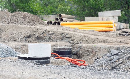 Téléchargez les photos : Installation d'un puits en béton armé pour l'alimentation en eau et l'assainissement. Site de construction avec un tas de gravats et de matériaux de construction - en image libre de droit