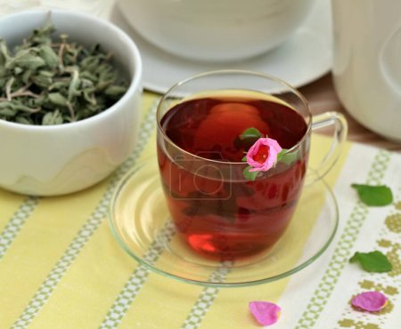 Cup of herbal infusion made from Cistus incanus, known as rock rose. Traditional curative herbal tea with many external and internal benefits. Dried leaves in bowl.