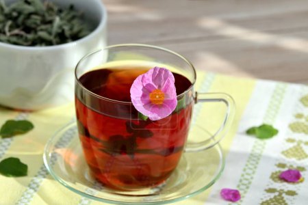 Cup of herbal infusion from Cistus incanus, known as rock rose. Traditional curative herbal tea with many external and internal benefits.  Dried leaves in bowl.