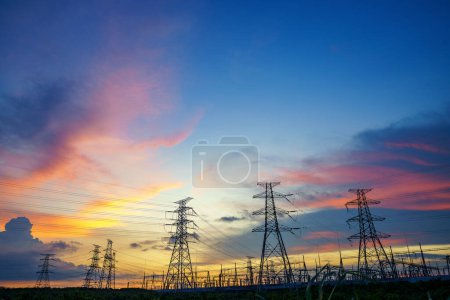 Stromübertragungsmasten in der Abenddämmerung vor blauem Himmel