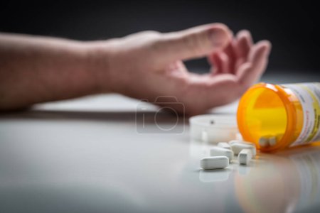 Photo for Man Passed Out on Floor Behind Scattered Drugs and Medicine Bottle. - Royalty Free Image