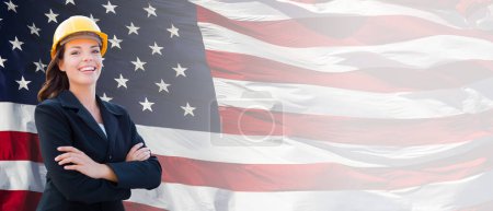 Photo for Female Contractor Wearing Blank Yellow Hardhat and Suit Over Waving American Flag Background Banner. - Royalty Free Image