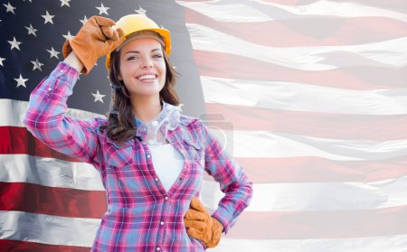 Photo for Female Contractor Wearing Blank Yellow Hardhat and Gloves Over Waving American Flag Background Banner. - Royalty Free Image