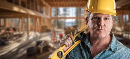 Téléchargez les photos : Entrepreneur masculin travaillant dur sur un chantier de construction portant un chapeau dur et des gants de travail tenant son niveau.. - en image libre de droit