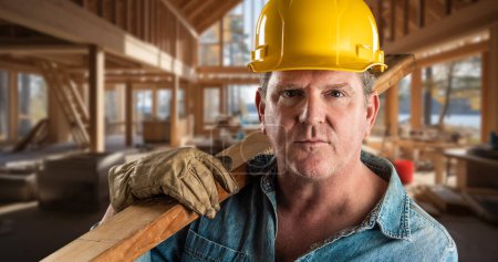 Foto de Contratista masculino en un sitio de construcción que usa un sombrero duro y guantes de trabajo que sostienen la madera 2x4 - Imagen libre de derechos