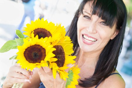 Téléchargez les photos : Happy Brunette Femme tenant un bouquet de tournesol fraîchement coupé au marché fermier. - en image libre de droit