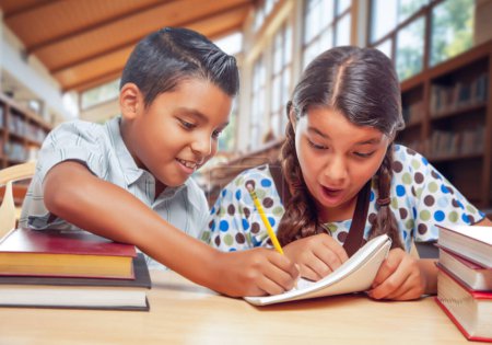 Photo for Two Hispanic School Kids in a Library Excited About Their Homework - Royalty Free Image