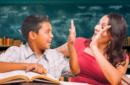 Photo for Latina School Teacher High Fiving a Young Hispanic Boy in the Classroom. - Royalty Free Image