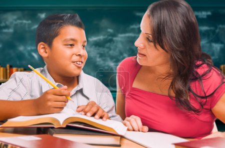 Photo for Female School Teacher Doing Homework with a Young Hispanic Boy in the Classroom. - Royalty Free Image