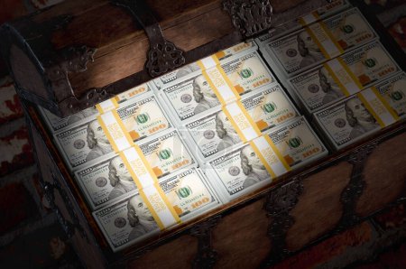 Foto de Linterna brillando en un cofre del tesoro lleno de millones de dólares en efectivo en una habitación oscura. - Imagen libre de derechos