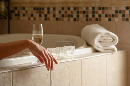Foto de Mujer Relajándose en el baño Bañera de hidromasaje con una copa de champán espumoso y velas. - Imagen libre de derechos