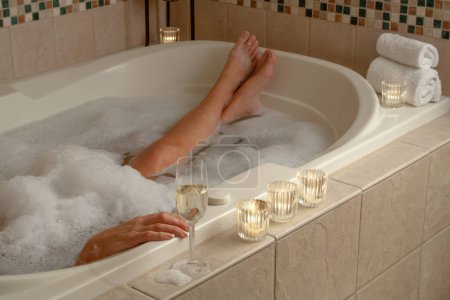 Photo for Woman Relaxing in the Bathroom Spa Tub with a Glass of Sparkling Champagne and Candles. - Royalty Free Image