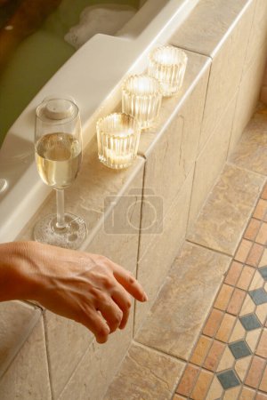 Téléchargez les photos : Femme Se détendre dans la salle de bain Baignoire spa avec un verre de champagne mousseux et des bougies. - en image libre de droit