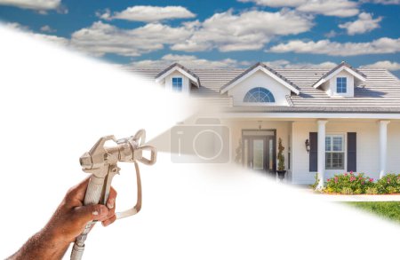 Téléchargez les photos : Peintre professionnel pulvérisateur tenant pistolet pulvérisateur pulvérisation nouvelle maison sur surface blanche. - en image libre de droit