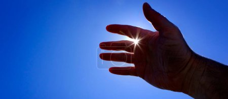 Photo for Hand reaching up towards heaven seeking help with sunstar sunshine inspiration guidance - Royalty Free Image