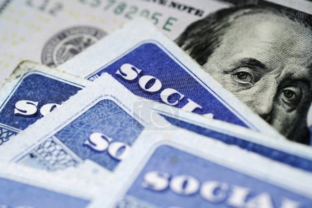 Plusieurs cartes de sécurité sociale sur un billet de cent dollars des États-Unis Système de prestations de 100 $pour les personnes âgées à la retraite