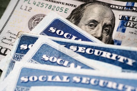 Plusieurs cartes de sécurité sociale sur un billet de cent dollars des États-Unis Système de prestations de 100 $pour les personnes âgées à la retraite