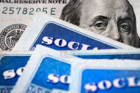 Photo for Several Social Security Cards on a US United States one hundred dollar bill $100 system of benefits for retired elderly people - Royalty Free Image