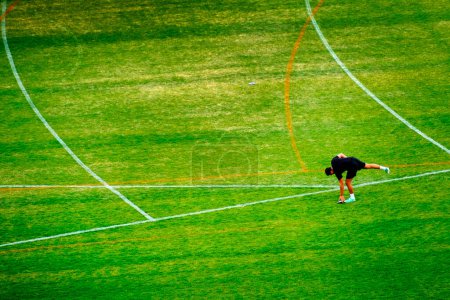 Photo for Discus throwing athlete for track and field picking up disc from green grass after throw - Royalty Free Image