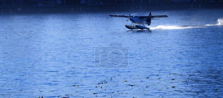 Photo for Sea airplane with pontoons taking off from water and flying propeller - Royalty Free Image