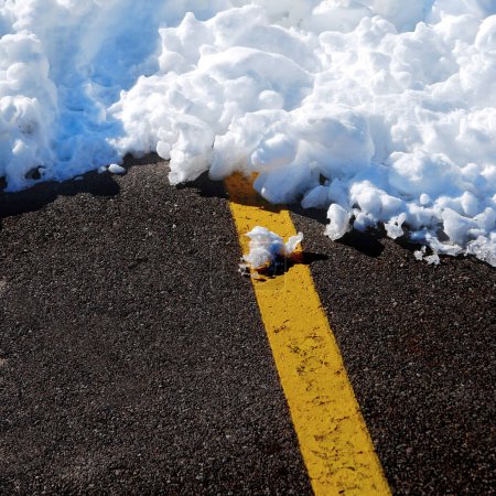 Snowy winter road or highway with yellow line and snow drift