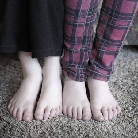 Téléchargez les photos : Pieds de deux enfants en pyjama pantalon trou jambes orteils - en image libre de droit