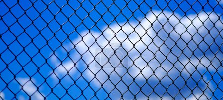 Chainlink fence detail with clouds and sky in background