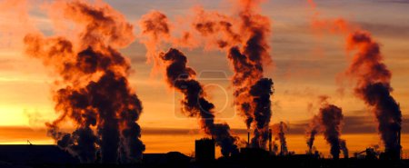 Factory with smokestaks pumping smoke pollution emissions into air lack of environmental concern environment at sunset