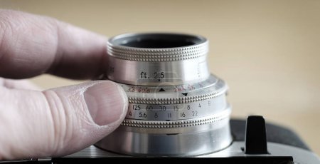 Téléchargez les photos : Vieil appareil photo avec un équipement de photographie à lentille manuelle pour capturer des images doigts changeant de réglages - en image libre de droit