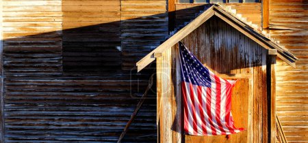 Téléchargez les photos : Vieux drapeau américain sur la porte en bois de bâtiment altérée - en image libre de droit