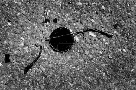 Broken smashed sunglasses on asphalt concrete road