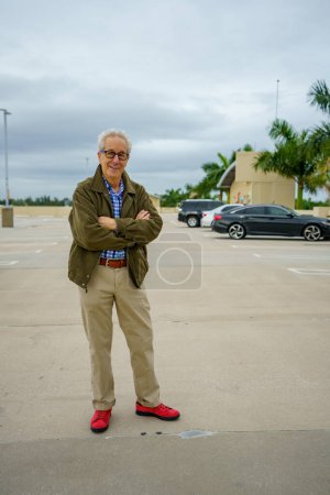 Foto de Senior man with a jacket posing with arms crossed in a parking lot - Imagen libre de derechos