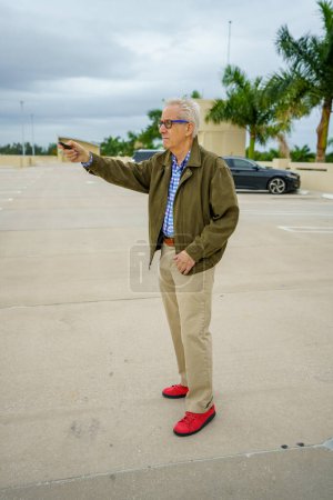 Foto de Old man looking for his car in a parking lot by pushing the unlock button on his fob - Imagen libre de derechos