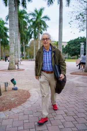 Foto de PHoto of a college professor walking on campus with blurry people in background - Imagen libre de derechos