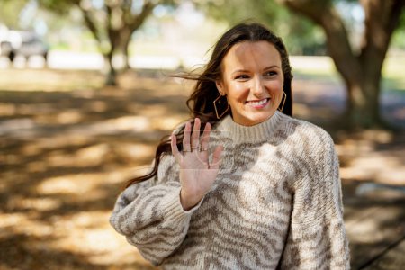 Photo for Happy care for young woman waving and smiling off camera - Royalty Free Image