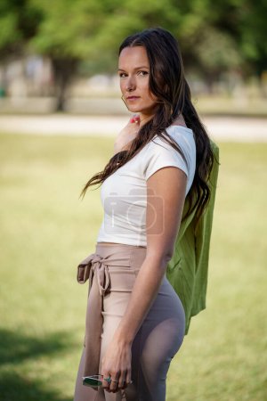 Téléchargez les photos : Photo d'une belle jeune femme dans la trentaine posant à l'extérieur avec une veste accrochée sur le bras - en image libre de droit