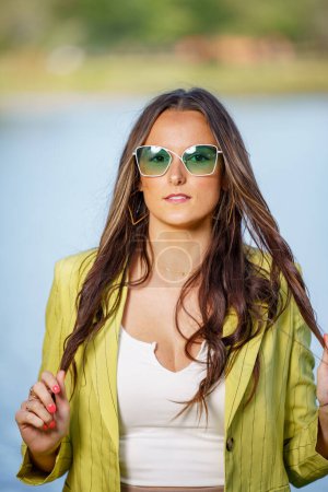 Foto de Modelo femenino joven retractivo posando en gafas de sol teñidas de verde - Imagen libre de derechos